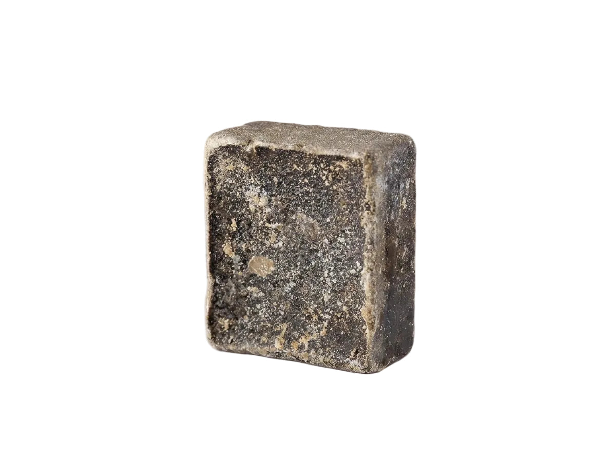 Mise en scène herboriste du musc solide entouré d'encens brut et d'étoffes d'hiver protectrices.