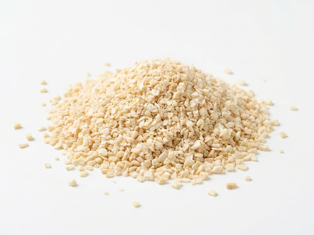 Gros plan sur les petits grains réguliers d'ail concassé séché, riches en huiles essentielles intenses.