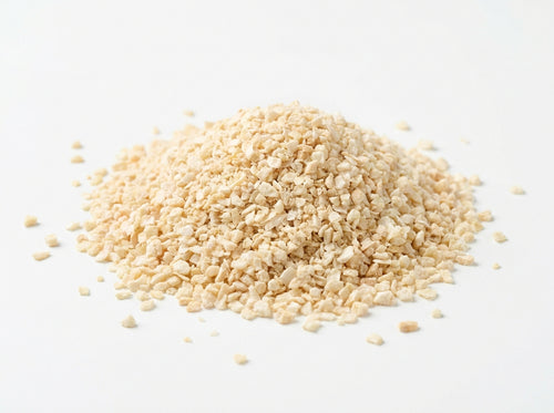 Gros plan sur les petits grains réguliers d'ail concassé séché, riches en huiles essentielles intenses.