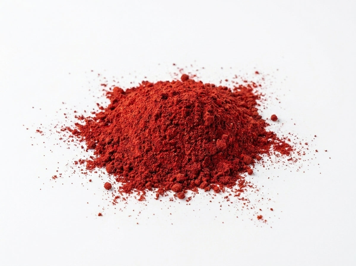 Gros plan herboriste sur la couleur rouge intense et la texture extra-fine de la poudre d'Aker Fassi micronisée.