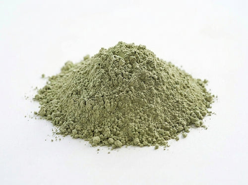 Gros plan herboriste sur la texture fine et minérale de l'argile verte séchée au soleil de chez Orianza.