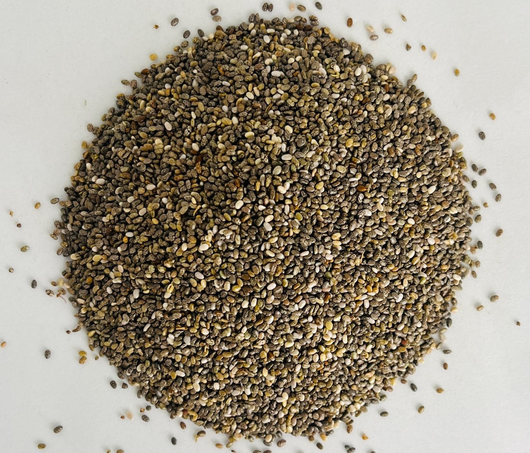 Gros plan macro ultra-détaillé sur la texture marbrée et la pureté des graines de chia bio d'Orianza.
