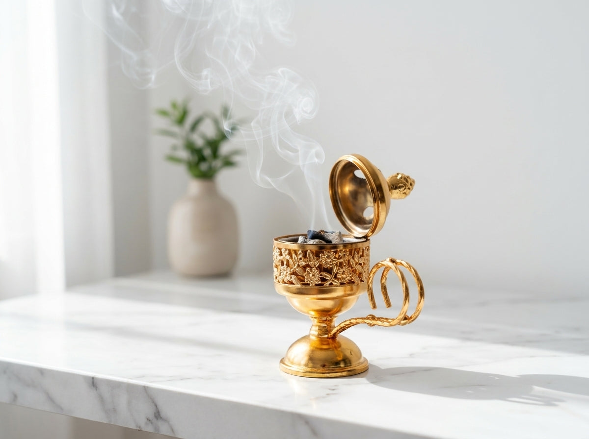 Volutes de fumée parfumées s'élevant délicatement à travers les motifs géométriques du petit encensoir métallique doré.