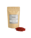 Sachet d'apothicaire en kraft de Hab El Aachak Orianza Selection, graines d'abrus rouges et noires avec quelques graines à côté.