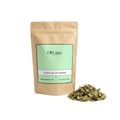 Sachet d'apothicaire en kraft de Feuilles de Henné Naturel Orianza Selection, soin capillaire pur avec quelques feuilles entières à côté.