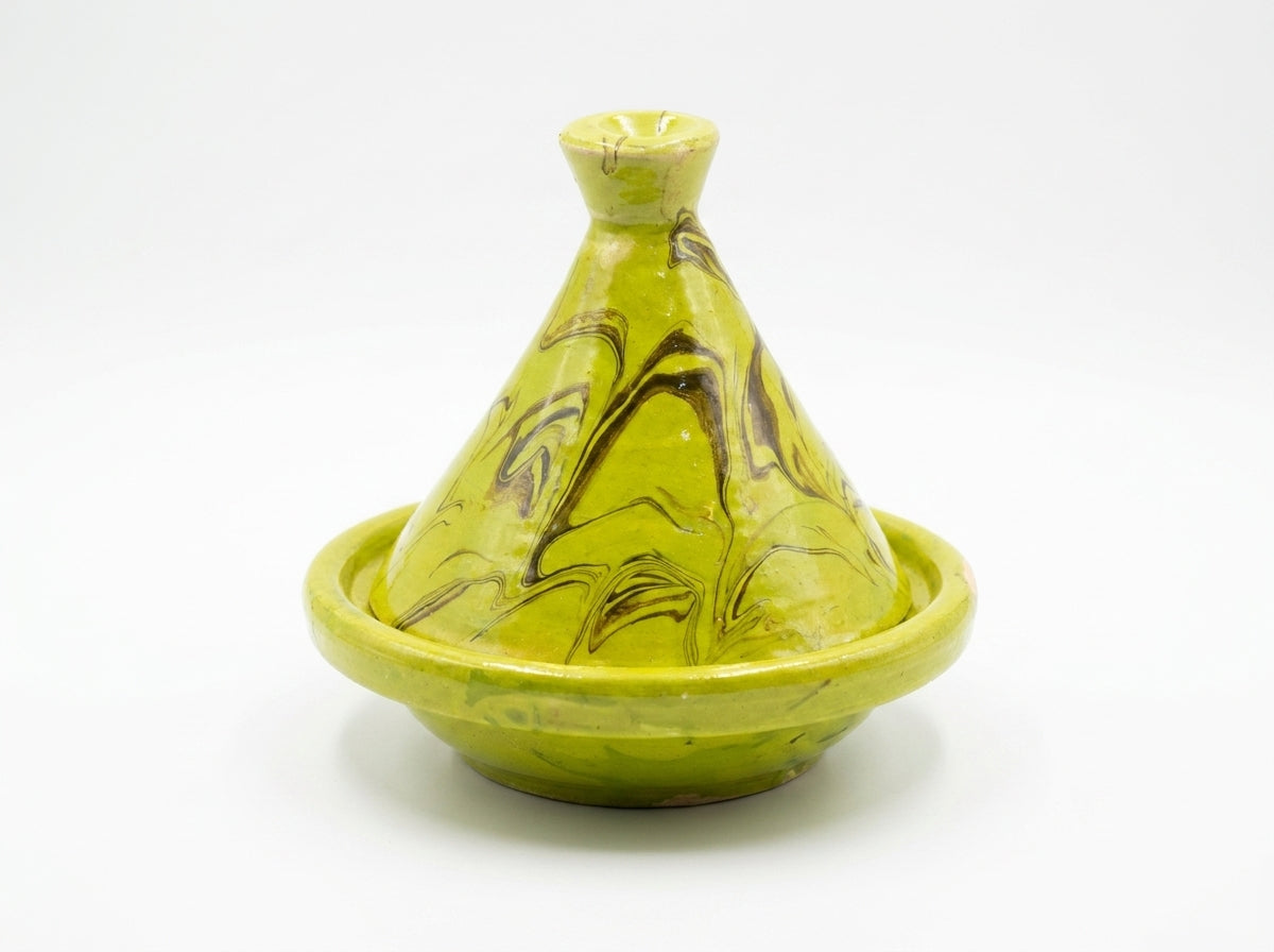 Petit tajine en terre cuite émaillée servant de porte-bijoux chic avec des bagues dorées déposées à l'intérieur.