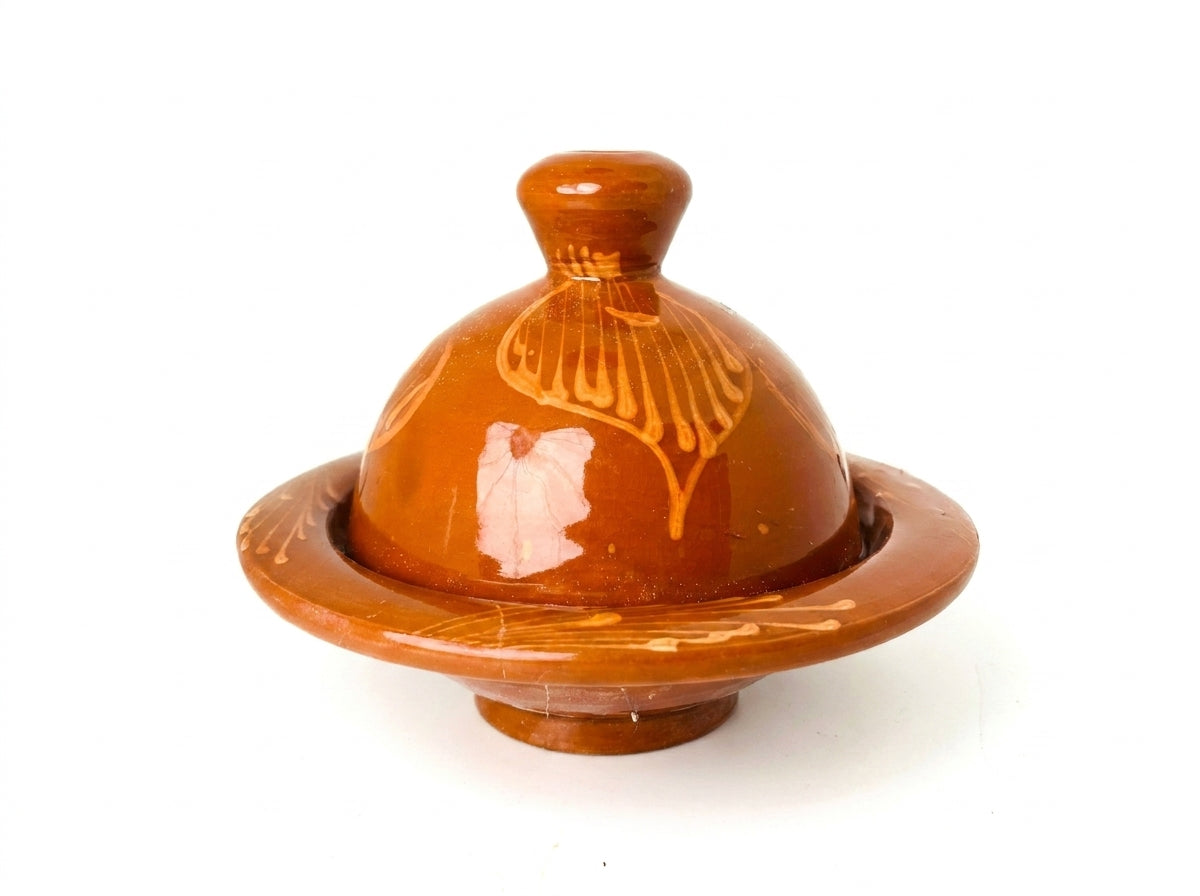 Mise en scène herboriste du mini tajine à côté de fleurs séchées et de stigmates de safran sur un plateau en cuivre.